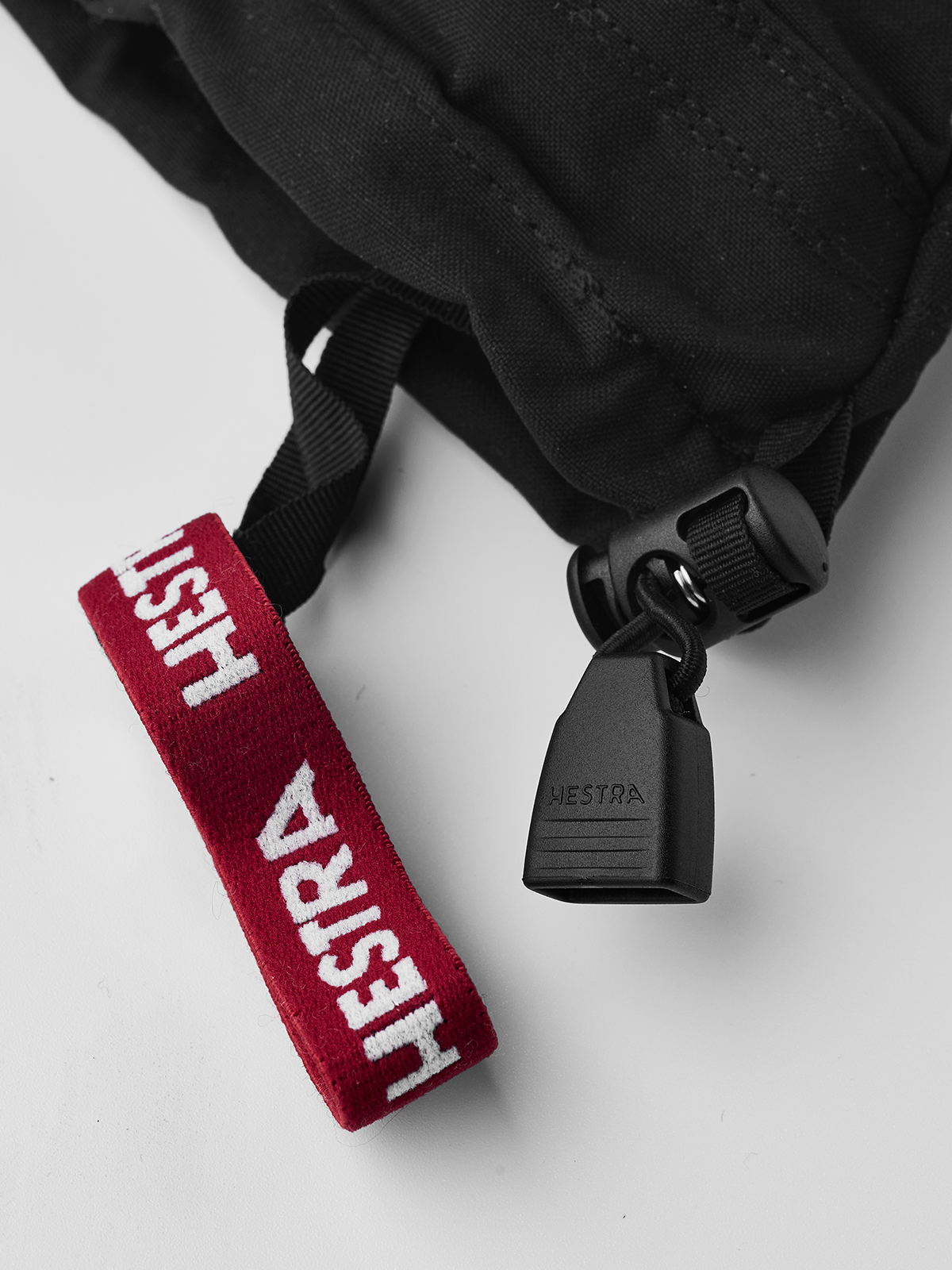 Junior ski glove close-up: red HESTRA strap with black plastic adjuster