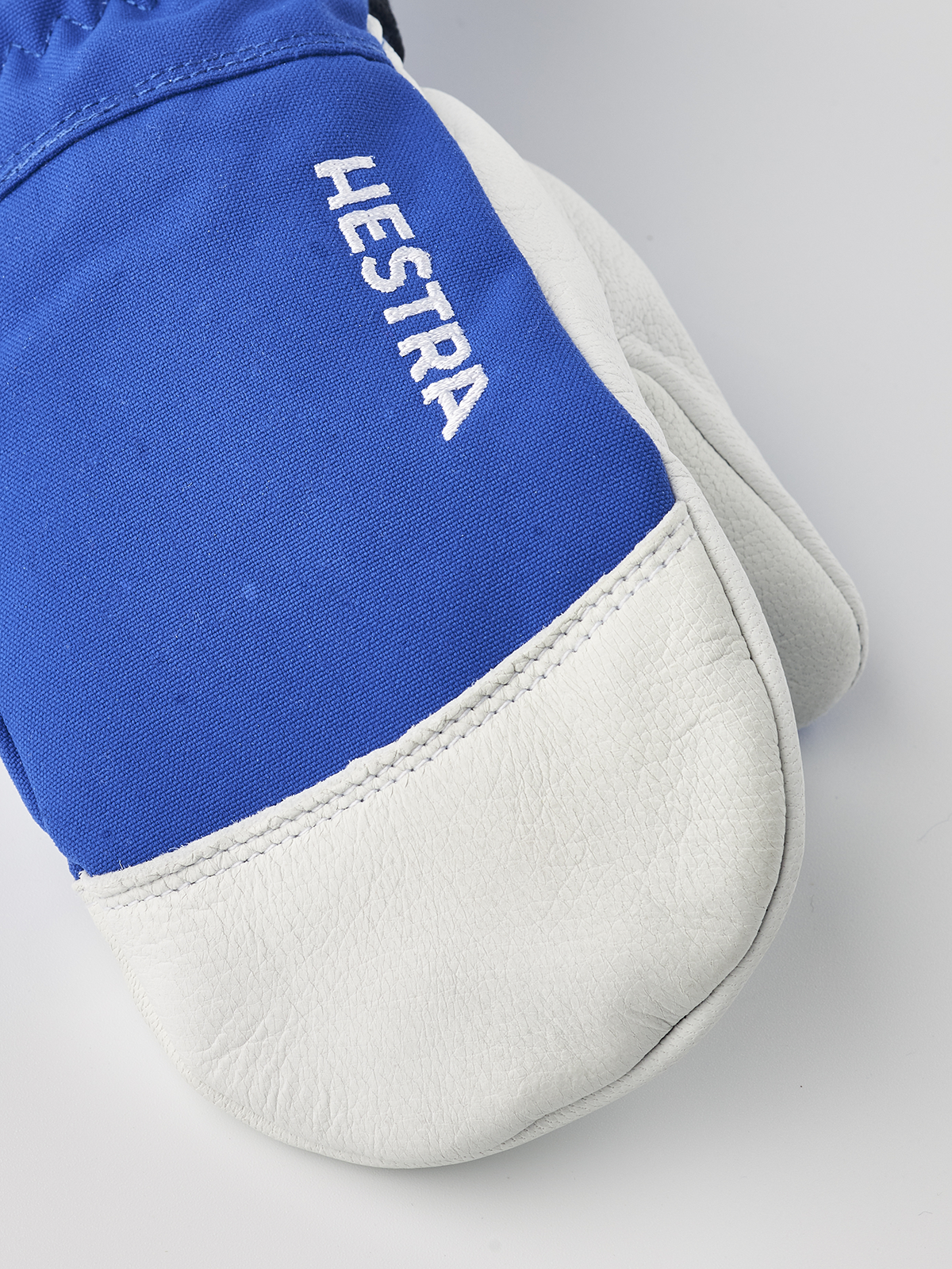 Blue junior ski mittens with white leather palm and Hestra logo on fabric