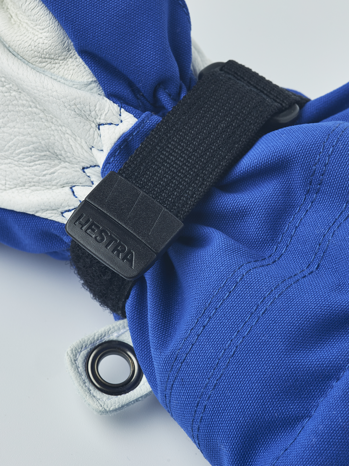 Blue junior ski gloves with white leather palm and black Hestra wrist strap