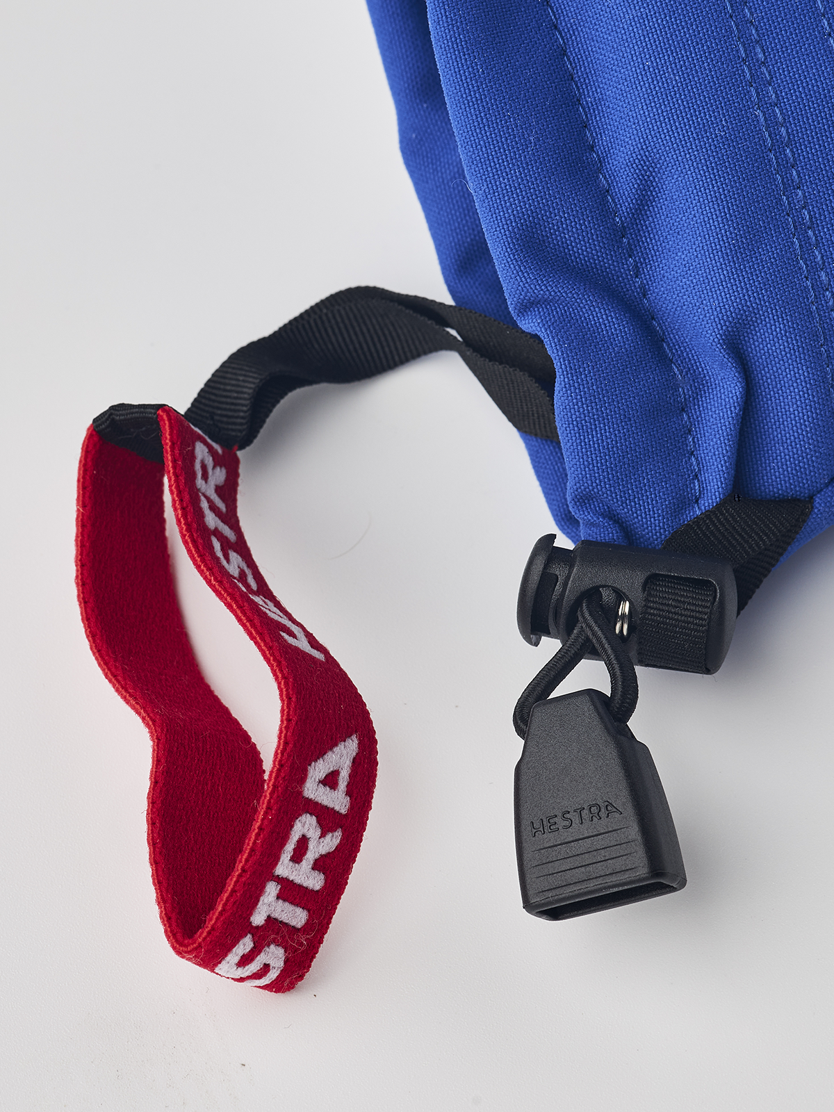 Junior ski mitten with blue shell, red HESTRA strap, and black adjuster clip