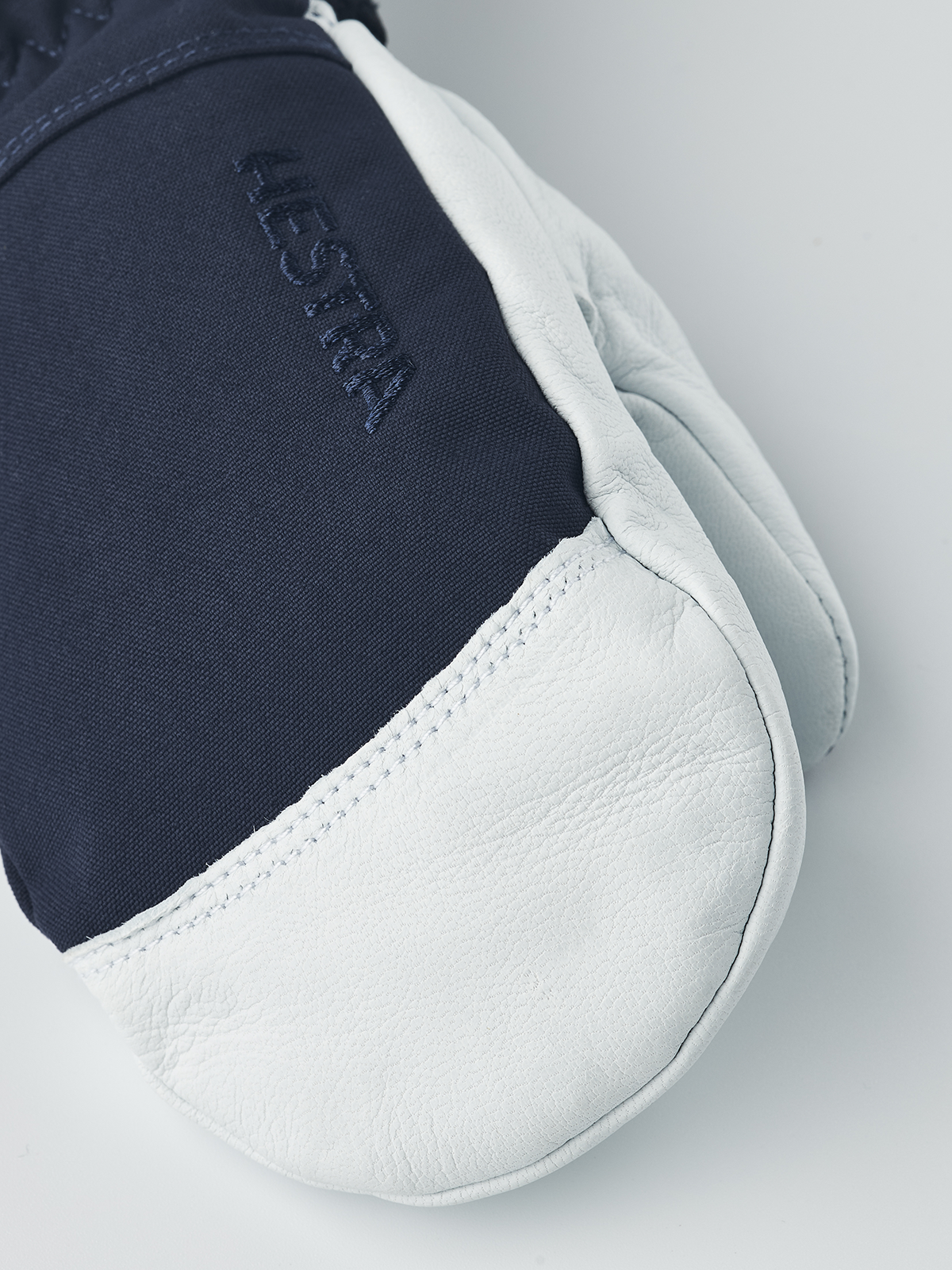 Navy blue junior ski gloves with white leather palm and stitched Hestra branding