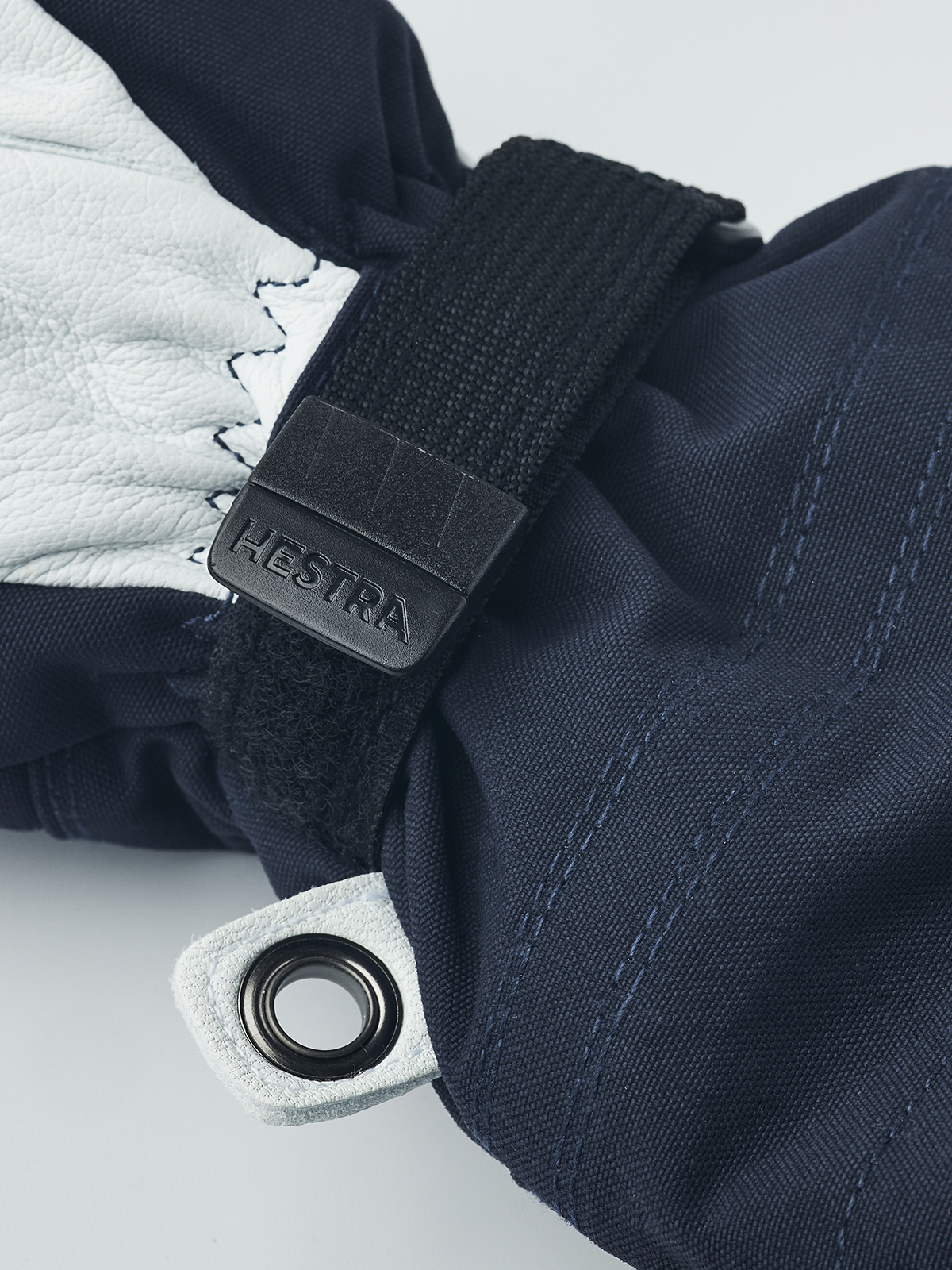 Navy blue junior ski gloves with white leather trim, black wrist strap, and loop