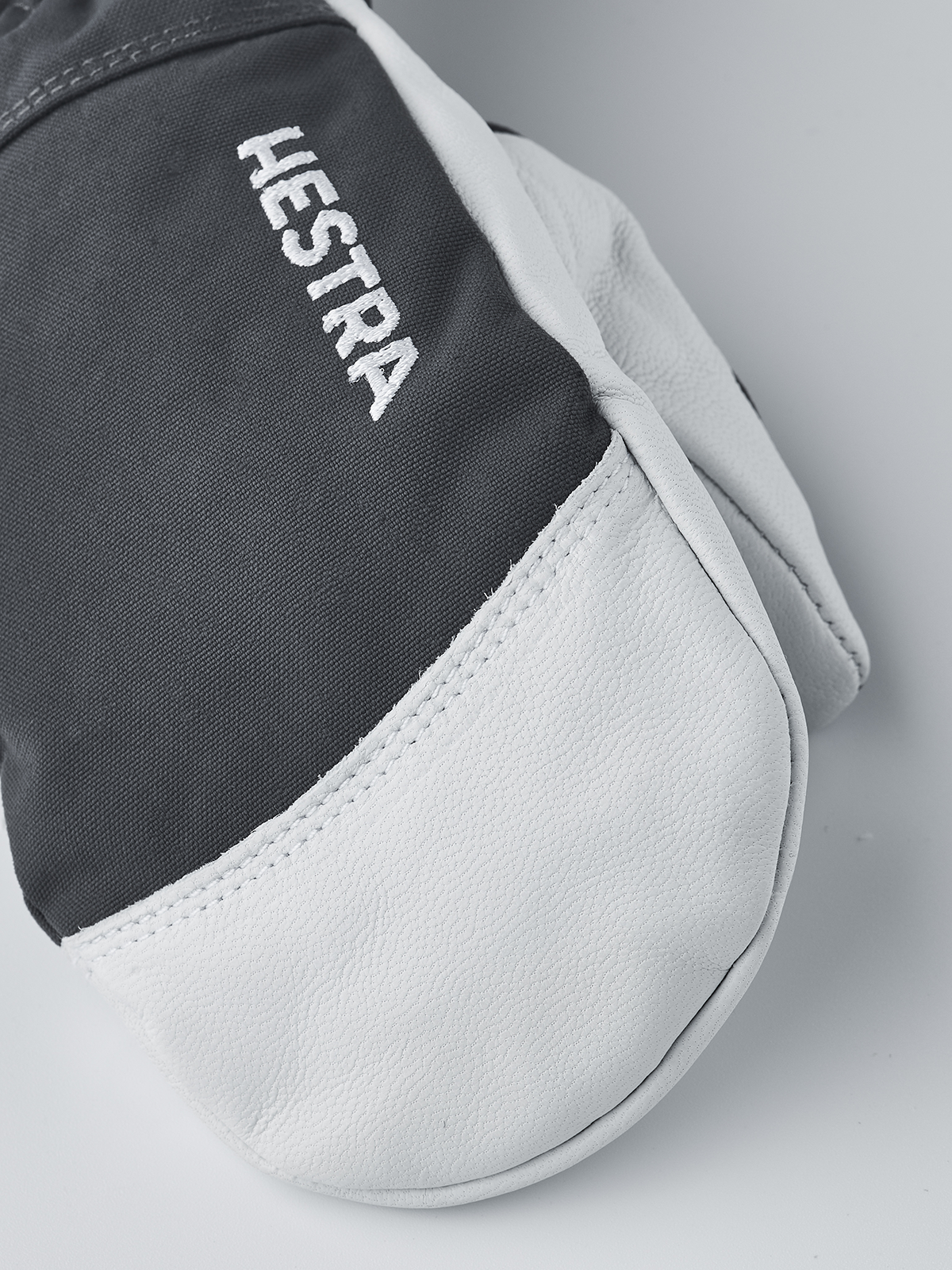 Junior ski glove close-up: white leather palm with black back panel showing HESTRA