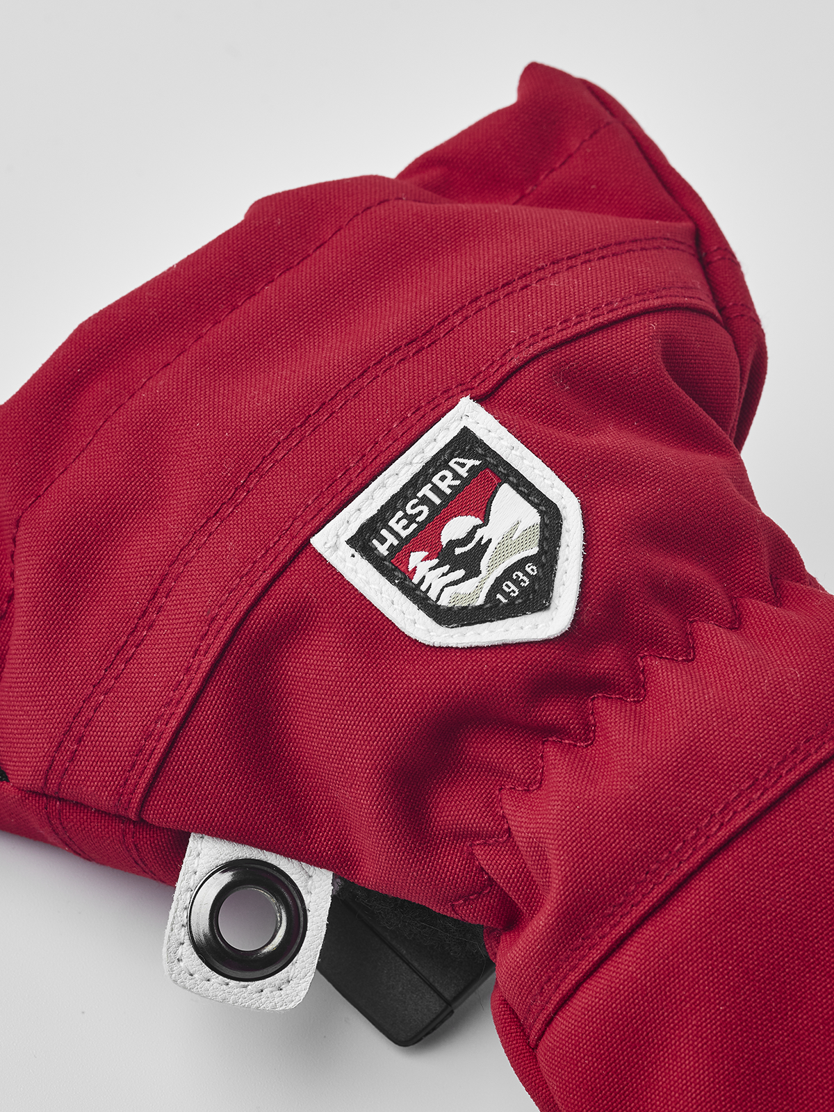 Kids ski mitten with red fabric, white-edged brand patch, and snap wrist closure