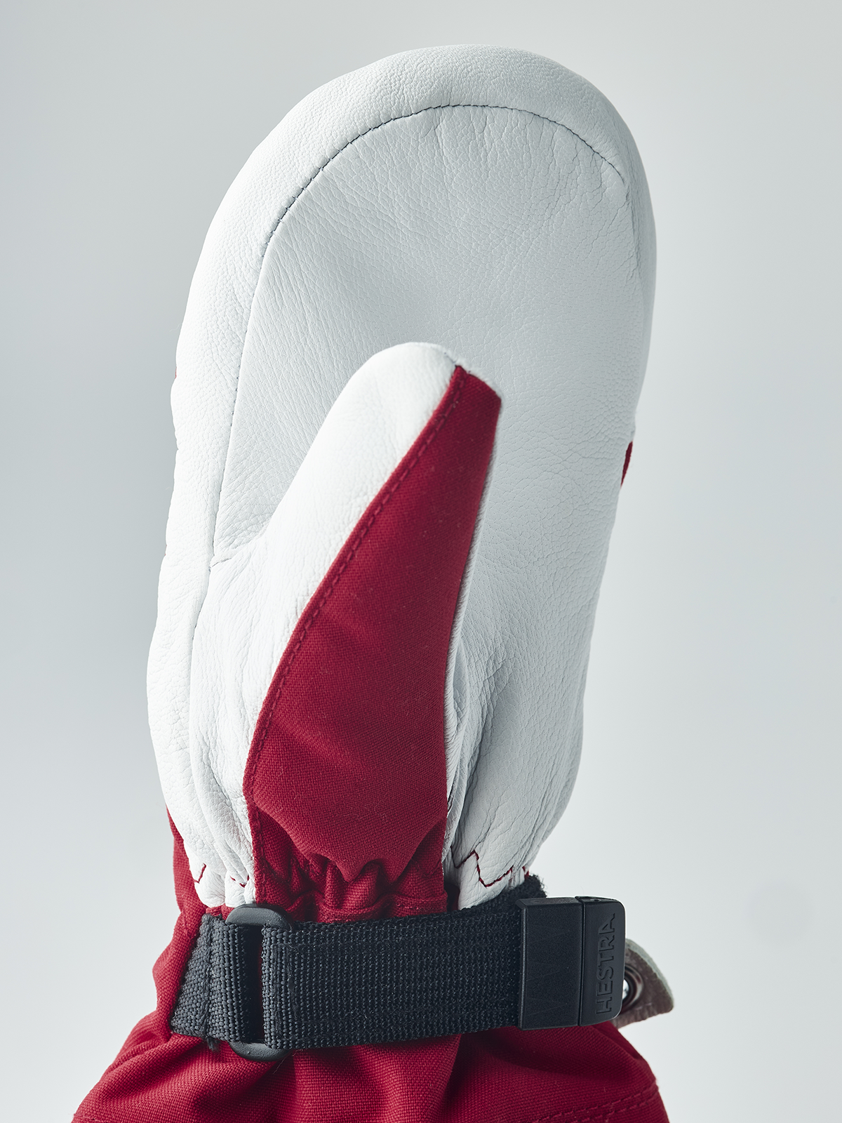 Kids ski mittens with white leather palm, red fabric accent, and black wrist strap