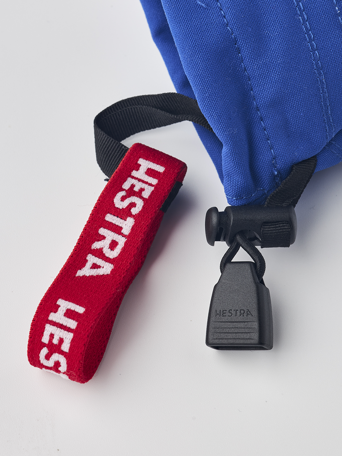 Junior ski mittens in royal blue with red “HESTRA” lanyard and black lock