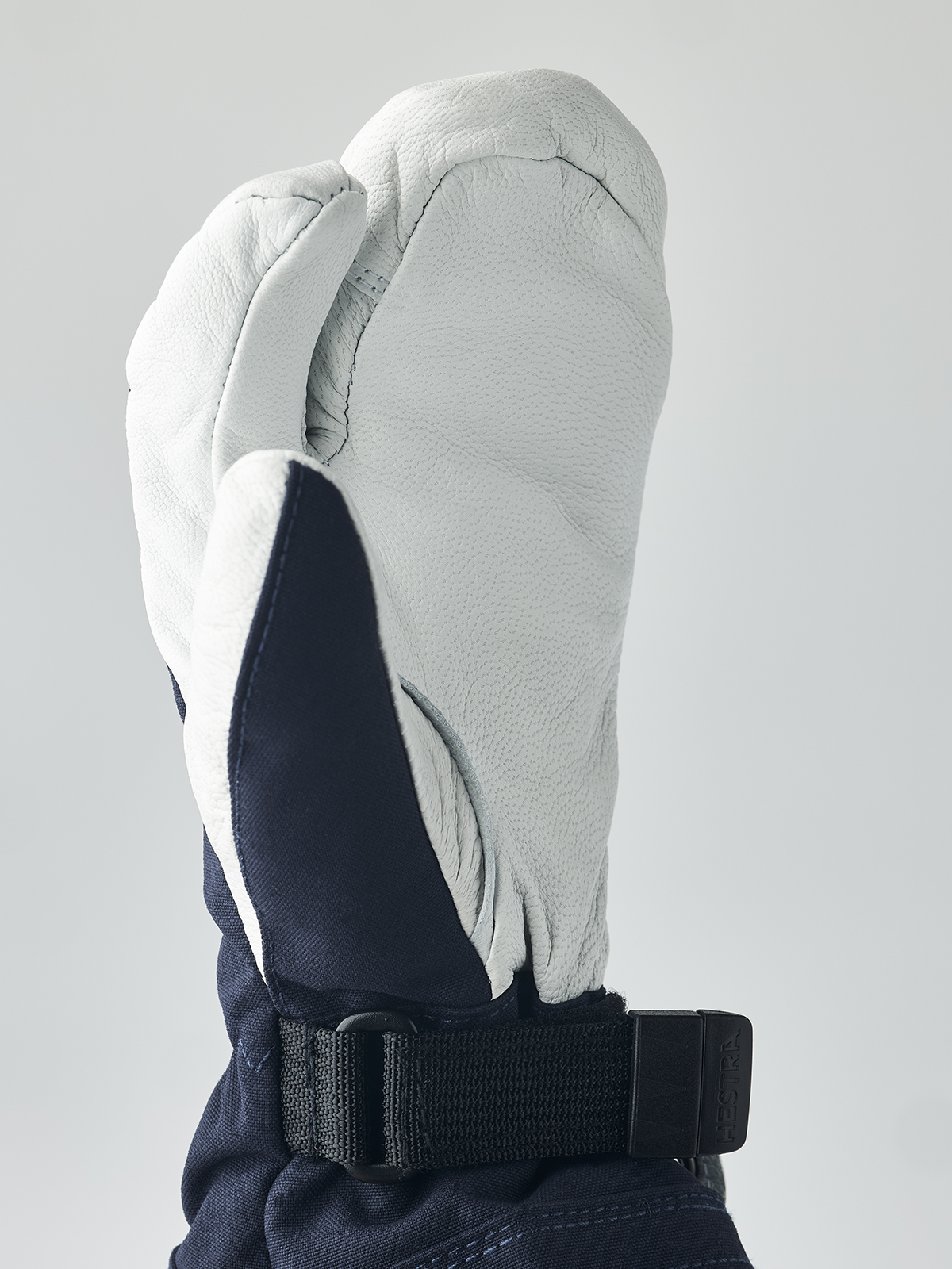 Hestra junior mitten in white with navy interior and black adjustable wrist strap