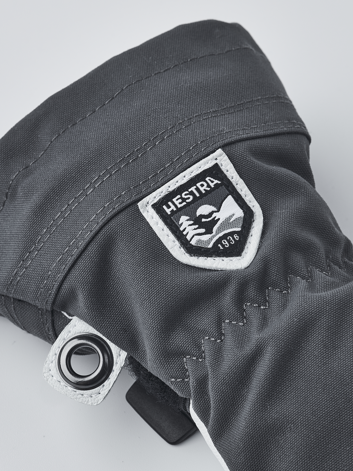 Hestra junior ski gloves in dark gray with Hestra logo patch and metal eyelet ring