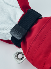 Hestra junior ski gloves in red with black wrist strap, metal eyelet ring, and fabric seams