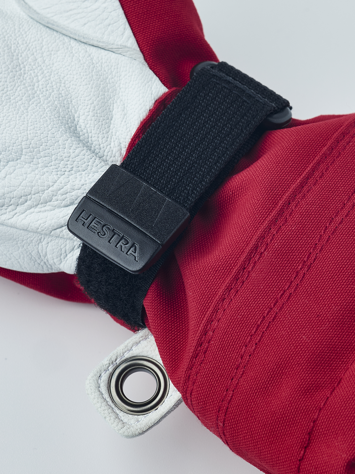 Hestra junior ski gloves in red with black wrist strap, metal eyelet ring, and fabric seams