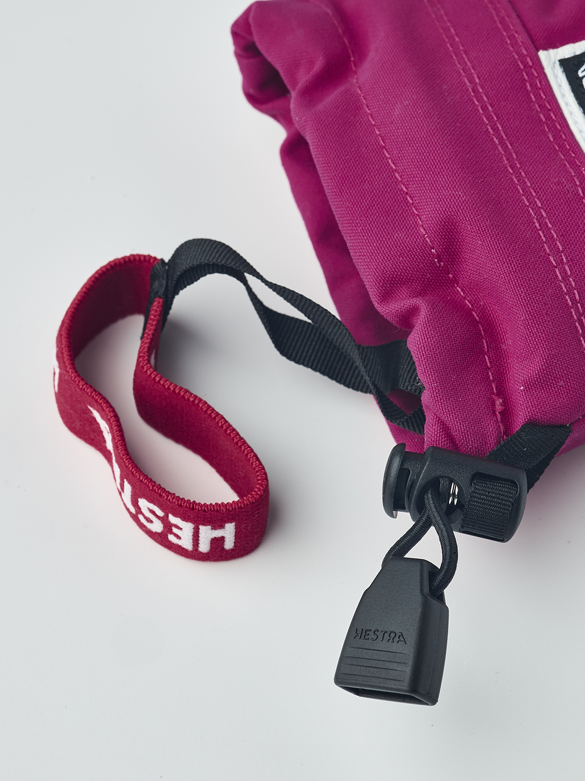Fuchsia junior ski mitten with Hestra tag, black pull clip, and red wrist loop