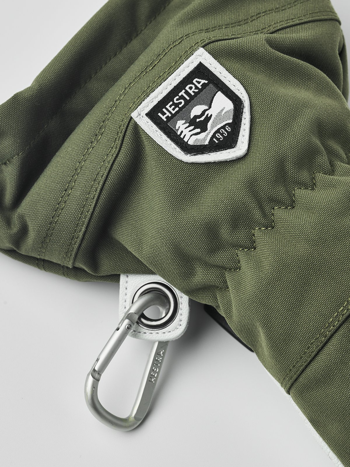 Olive ski glove with HESTRA shield patch and metal carabiner ring