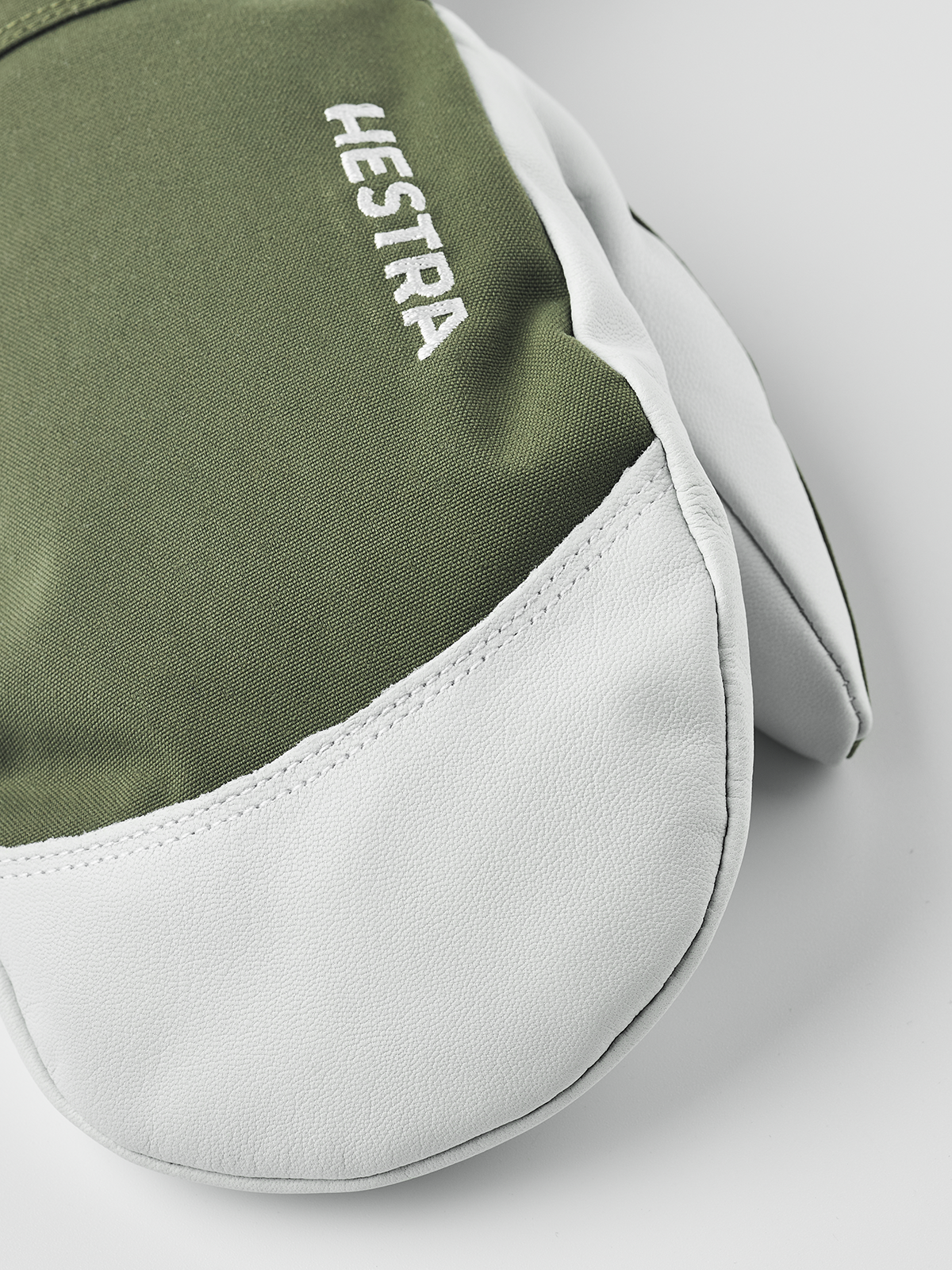 Olive green and white Hestra ski mittens with embroidered logo on the back
