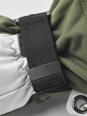 Olive and white Hestra ski glove with black wrist strap and metal ring