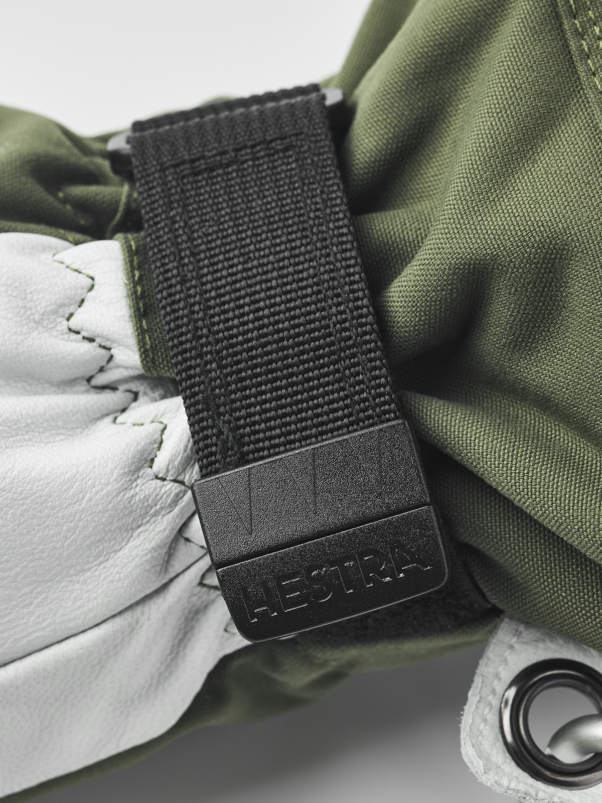 Olive and white Hestra ski glove with black wrist strap and metal ring
