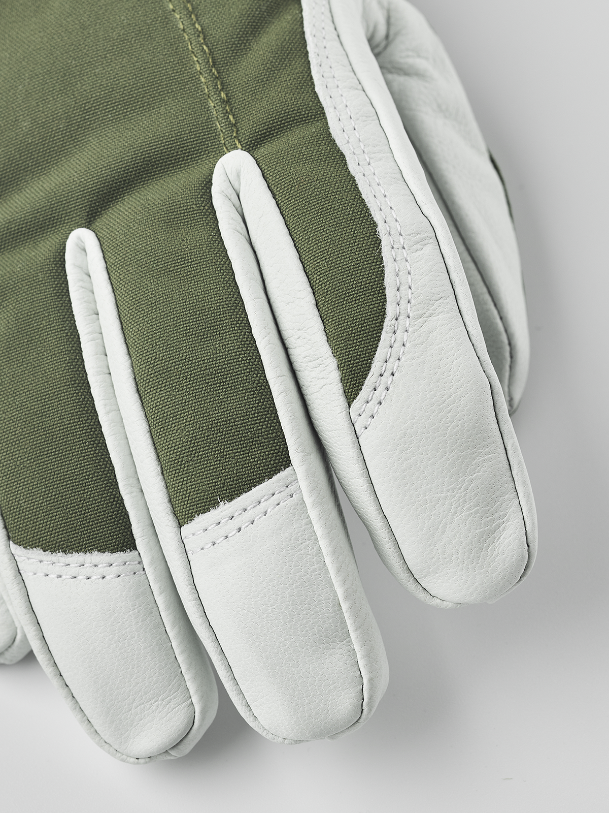 Olive green ski gloves with white leather palm and curved finger seams