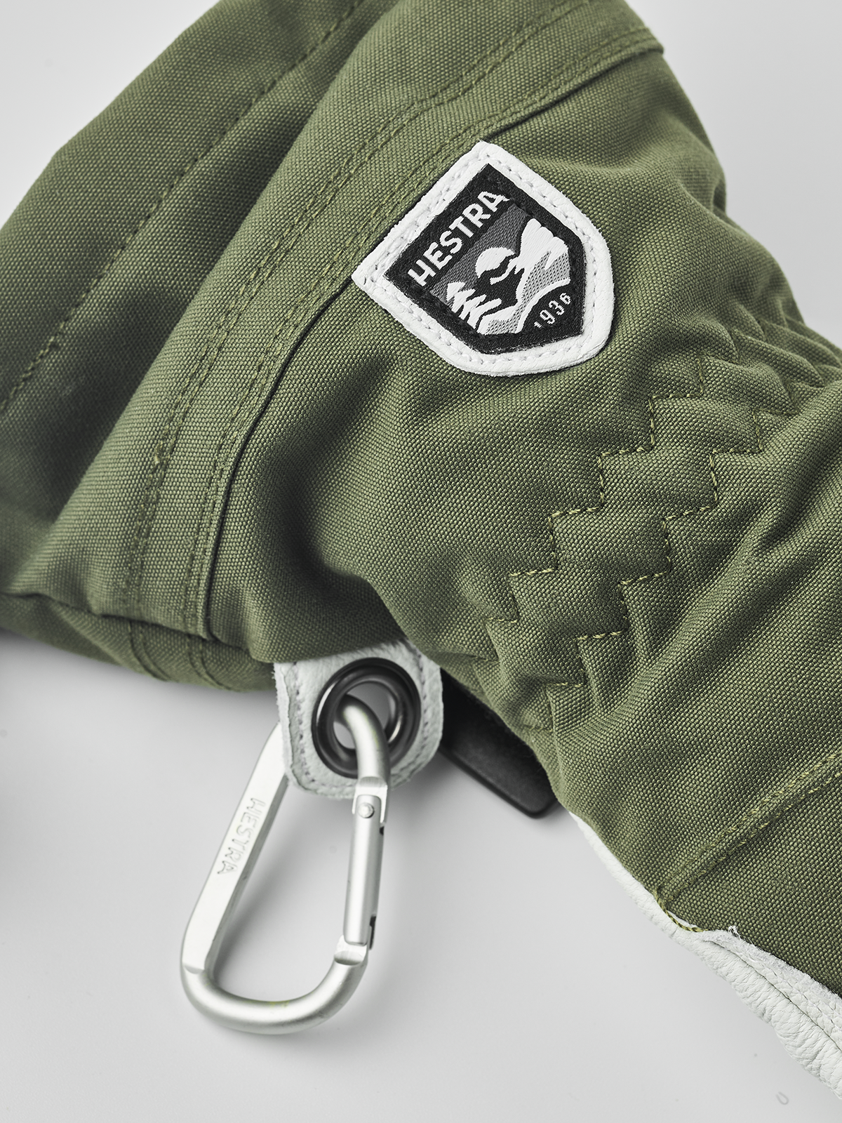 Hestra Heli ski gloves in olive green with Hestra logo patch and carabiner clip