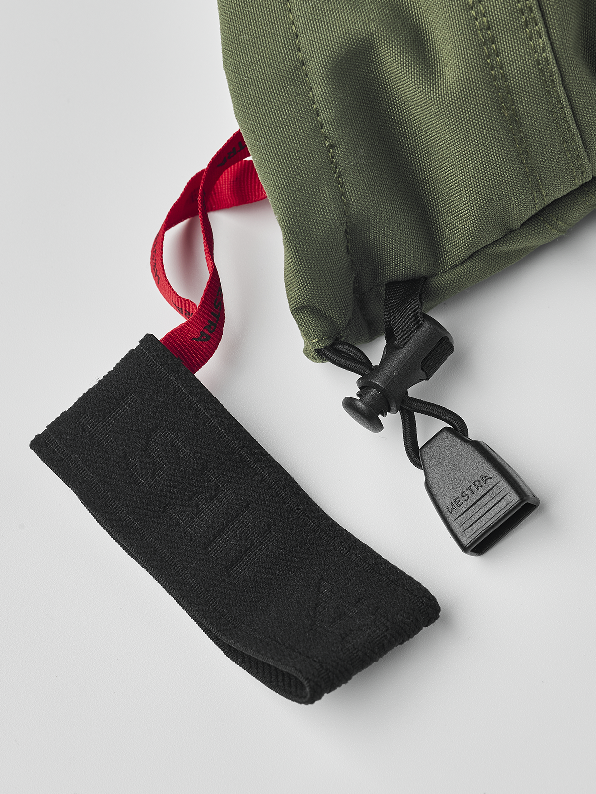 Olive ski glove with black wrist pull strap and black Hestra tag