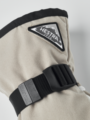 Beige powder gauntlet mitten with black cuff strap and Hestra logo patch