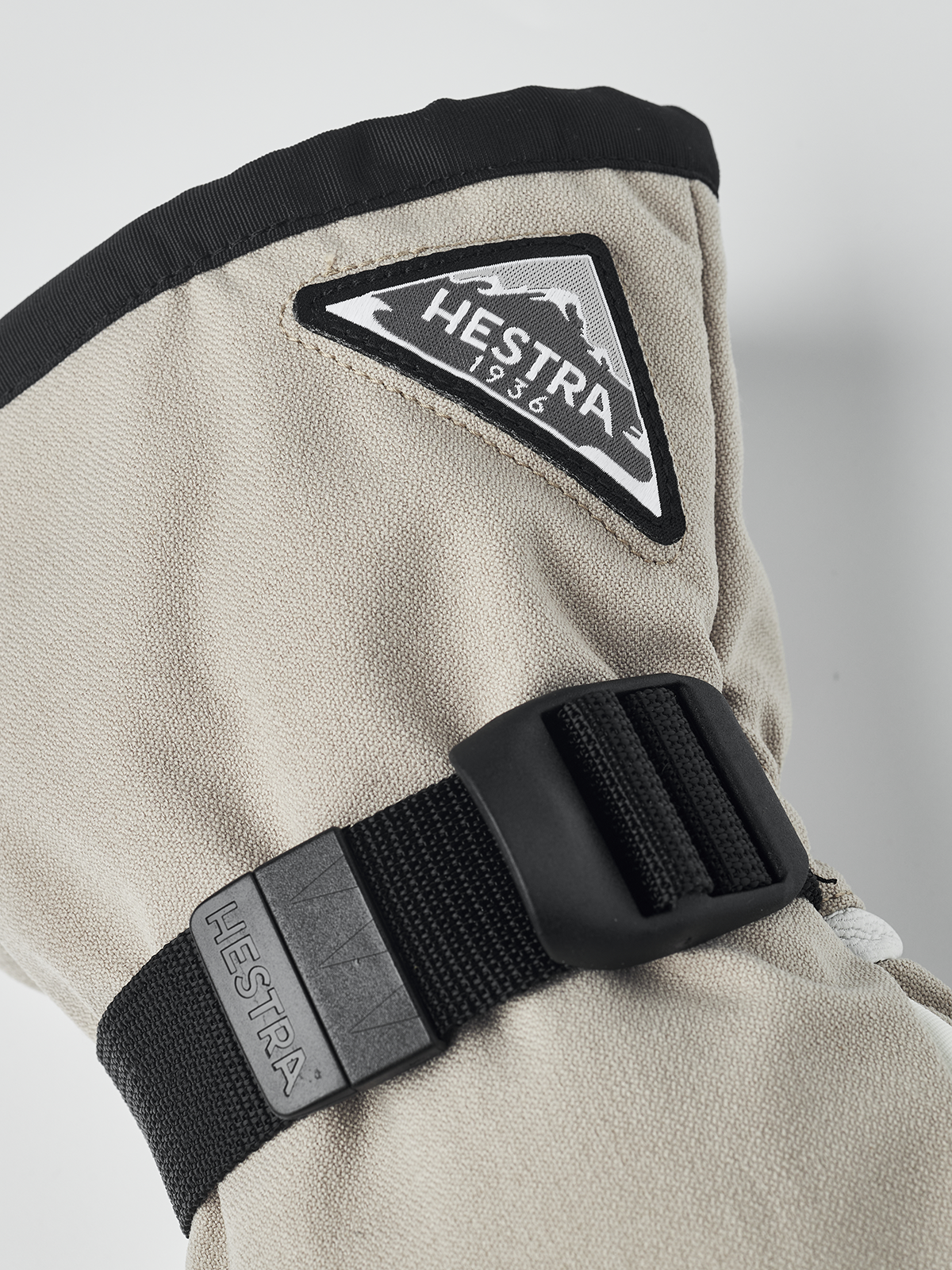 Beige powder gauntlet mitten with black cuff strap and Hestra logo patch