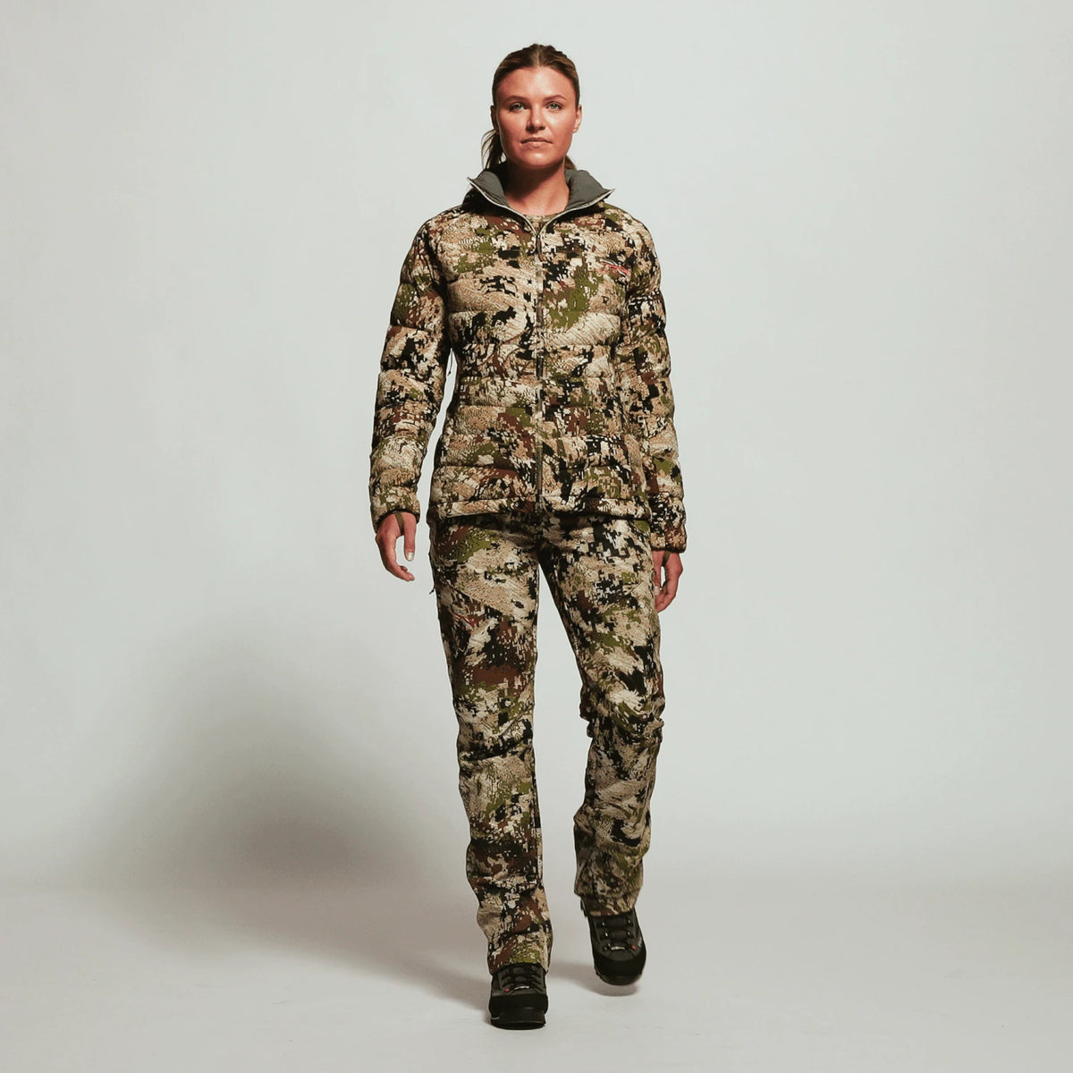 SITKA Gear women's Kelvin Lite down jacket worn with camo pants, full outfit view