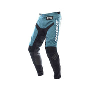 Youth motocross pants in teal and black with protective knee panels, Fasthouse logos.