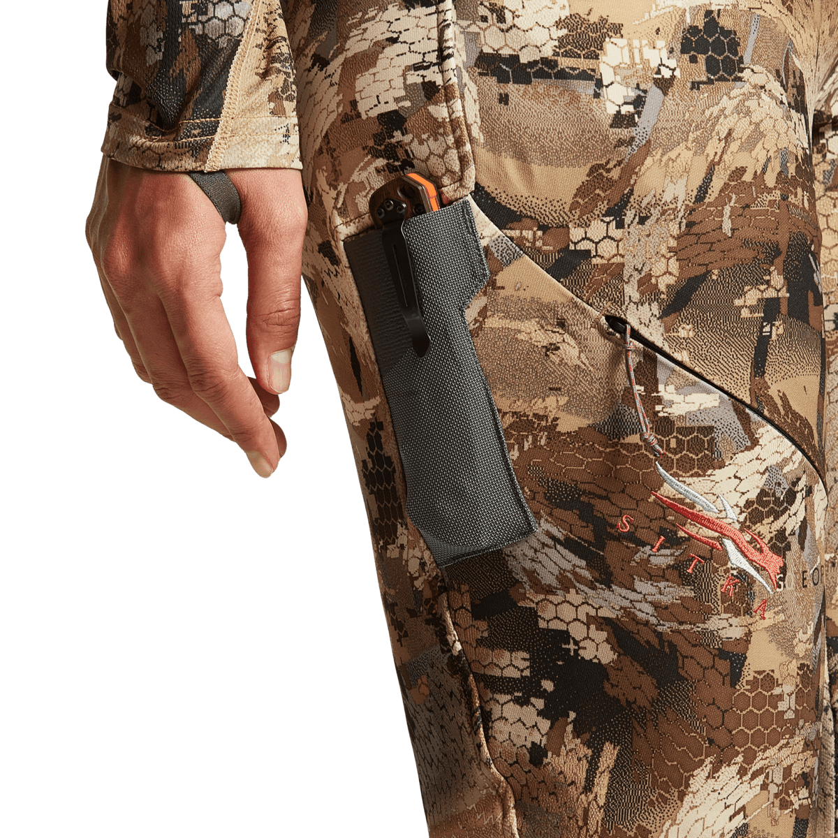 Hunting pants with camo fabric and zippered leg pocket with gray fabric panel