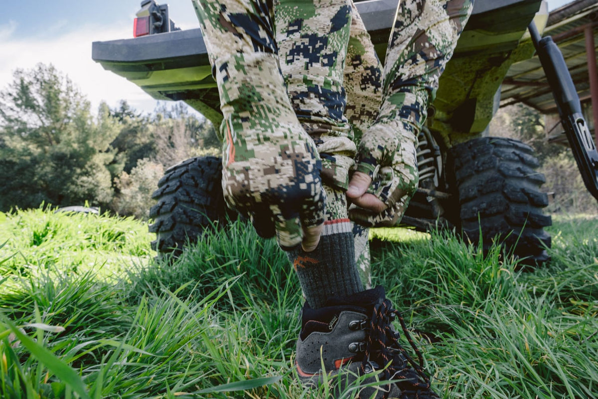 Men's camouflage hunting pants in green-brown pixel pattern, full-length view.