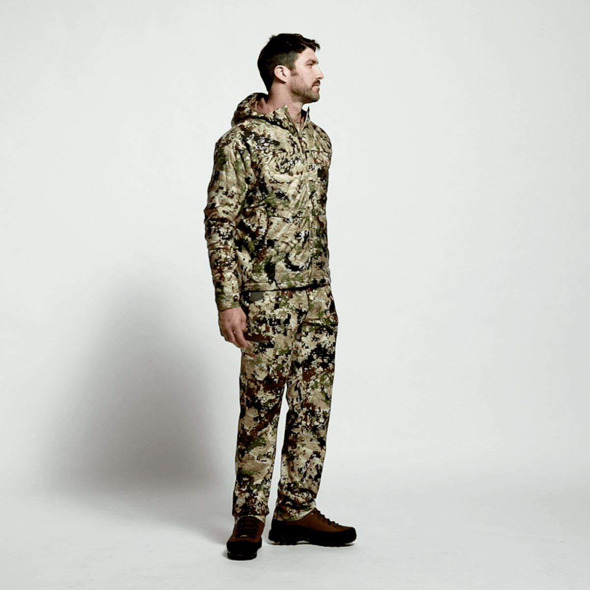 SITKA camo hooded hunting jacket set on model, standing side view.