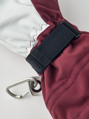 Burgundy ski glove with black wrist strap and metal carabiner clip.