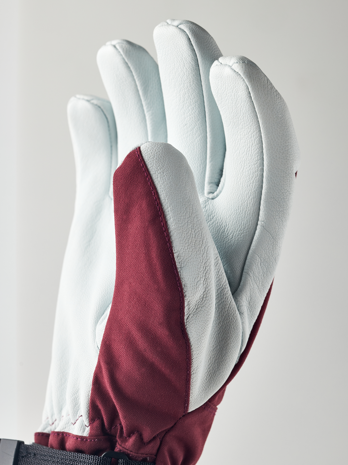 Light blue ski glove with maroon inner panel and protective padded back.