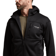 Black hooded zip jacket close-up: chest pocket, zipper pull, and small logo