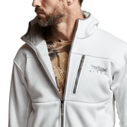 White zip hoodie worn open, showing inner camo fabric at neckline