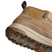 Tan boot tread outsole close-up with deep lugs and white midsole edge