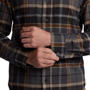 Close-up of lightweight flannel plaid shirt fabric in dark navy, brown, and tan with button cuffs