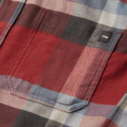 Red plaid flannel shirt fabric close-up with topstitched pocket and button placket