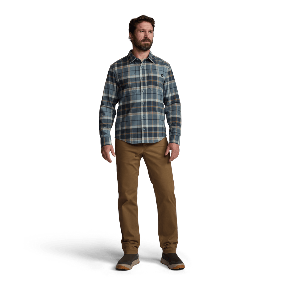 Man standing in blue plaid lightweight flannel button-up with tan pants