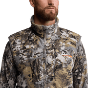 Tan-and-gray camouflage zip-up hunting vest with chest pocket flap, close-up