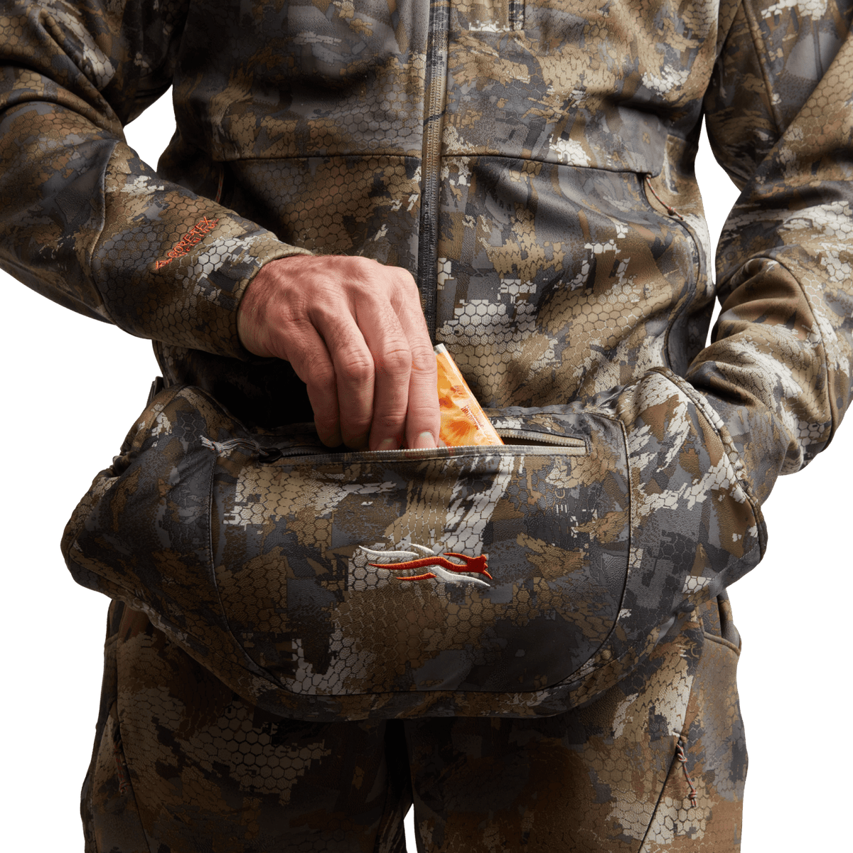 Hand placing inside camo insulated muff; orange pull tab on zipper