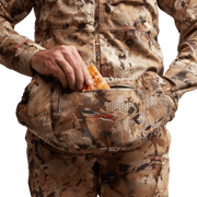 Hand reaching into camo insulated muff; zipper area visible