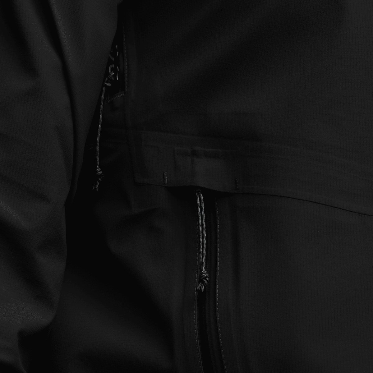 Black jacket fabric close-up with zipper seam and stitched panel