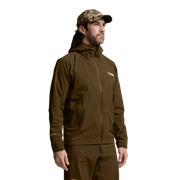 Solid brown hooded jacket worn on model, front zipper and chest logo