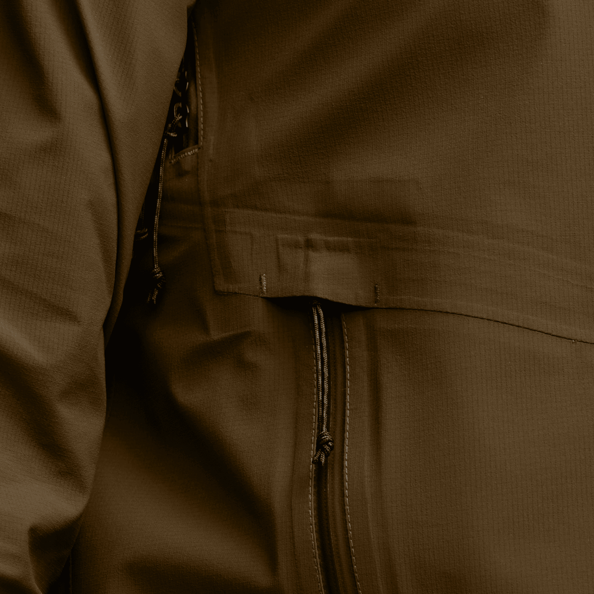 Tan jacket close-up of chest pocket flap and zippered seam detail