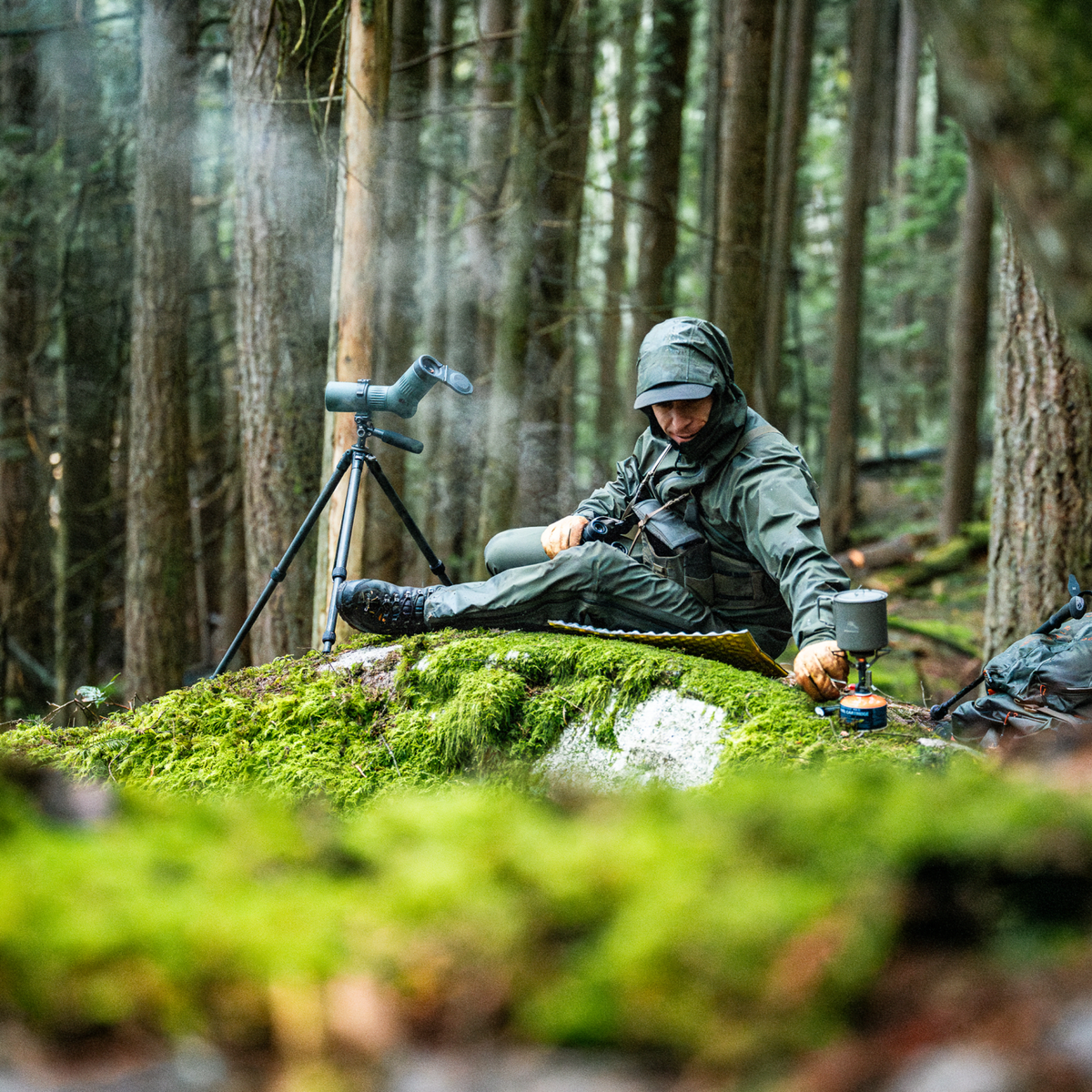 Camouflage hooded jacket worn outdoors in forest while cooking