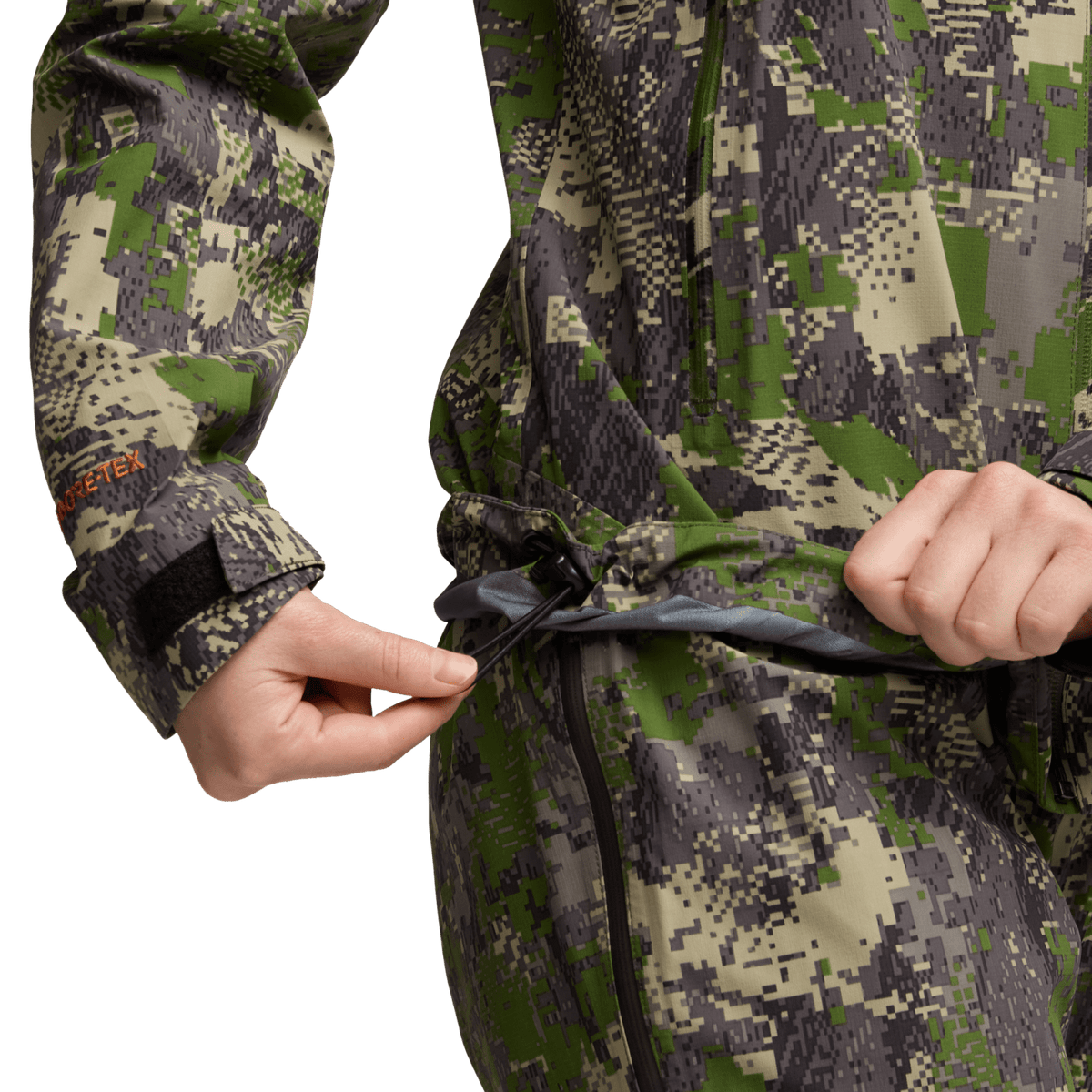 Women’s camo jacket detail, hands pulling drawcord at hood hem