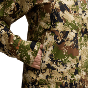 Digital camouflage jacket sleeve close-up with front zipper and hand near cuff