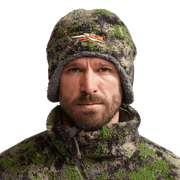 Green and dark brown camouflage fleece beanie with orange logo on wearer's head