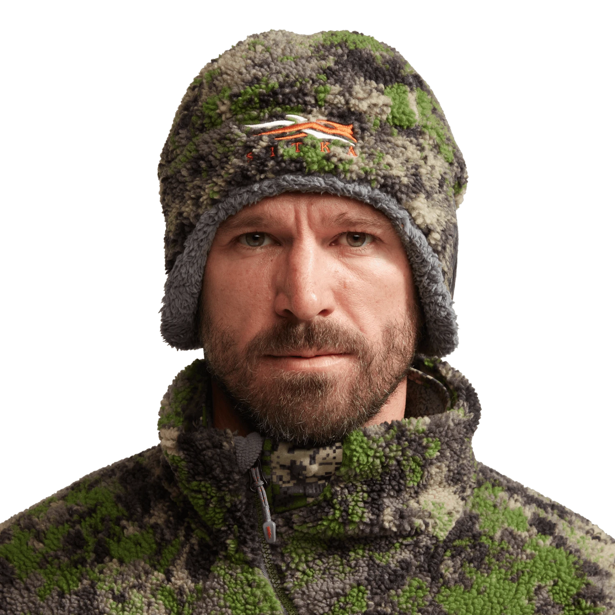 Green and dark brown camouflage fleece beanie with orange logo on wearer's head