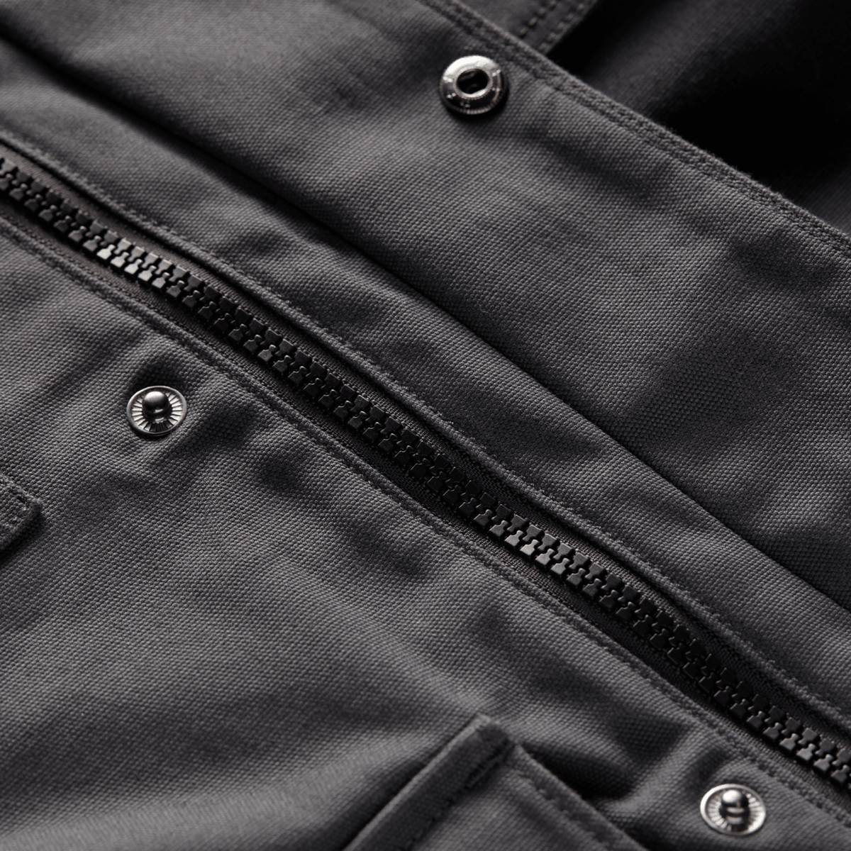 Gray chore coat detail with zippered front placket and metal snap buttons