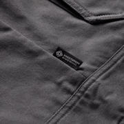 Iron grey chore coat label at chest seam, with stitched collar edge and fabric texture.